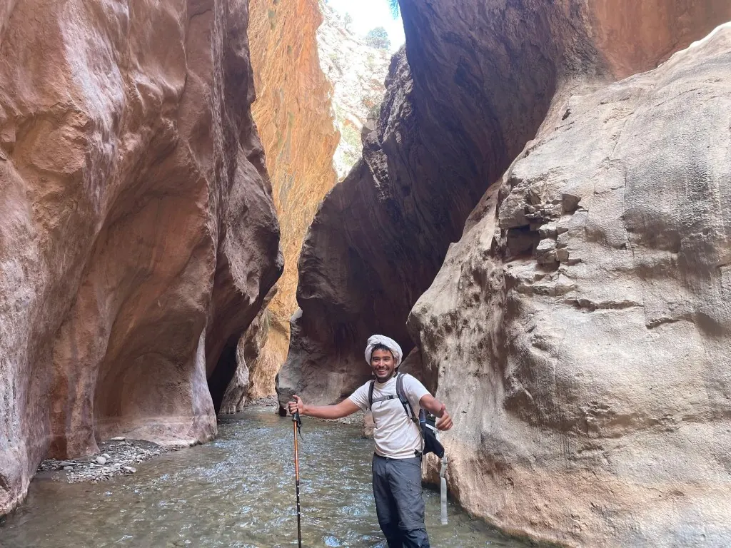 Ahmed in a Moroccan gorge, giving a thumbs up while wading through a river