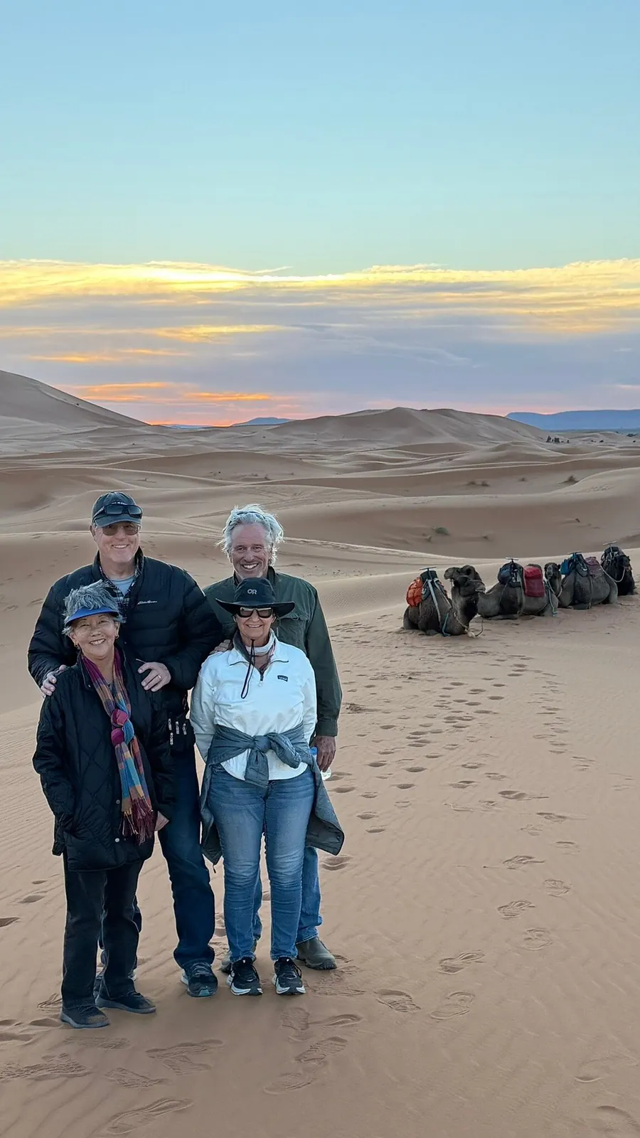 Lisa A and friends on a desert dune at sunset with camels in the background