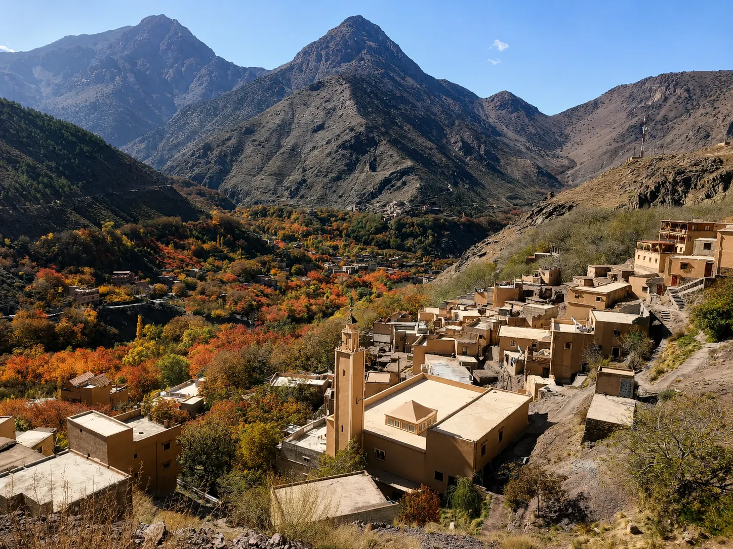 High Atlas Berber village with autumn colours and a mosque minaret against mountain peaks