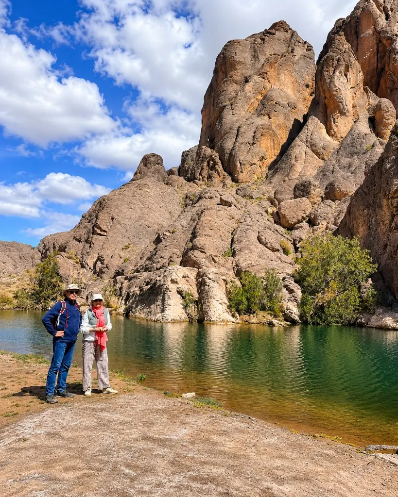 Travellers beside a turquoise oasis pool in a rocky canyon