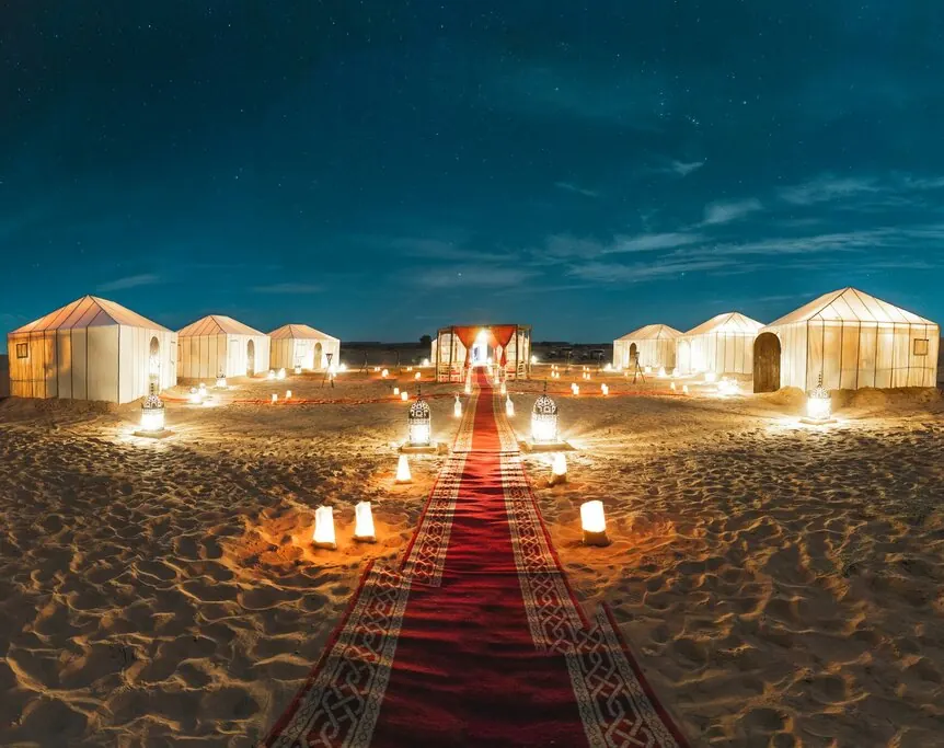 Luxury Berber desert camp panorama with candle lanterns at night