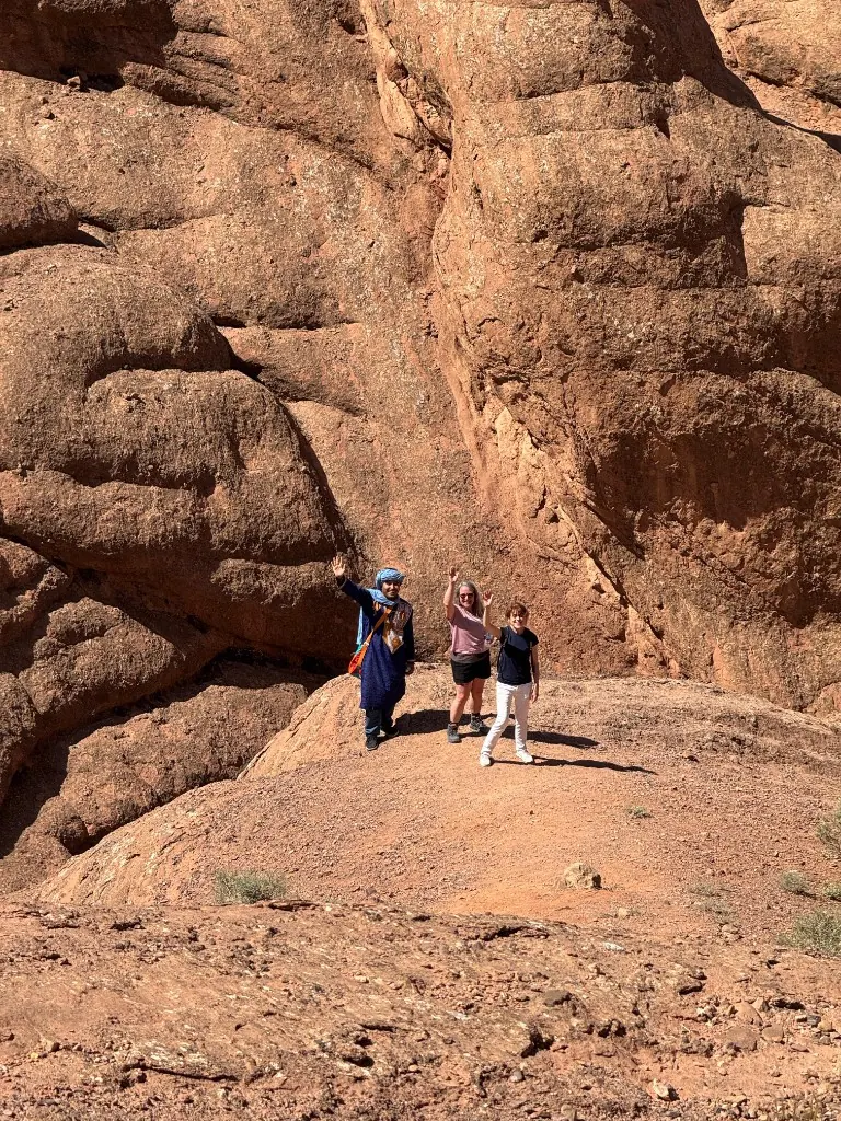 Travellers and their guide waving from a rocky outcrop at the Todra Gorge