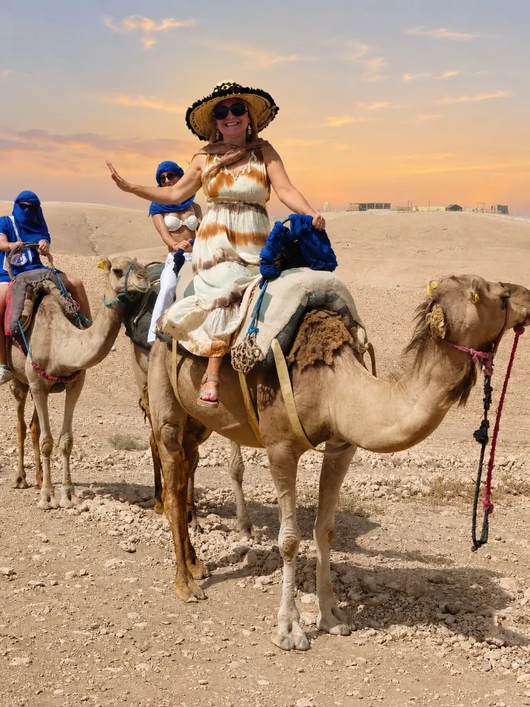 Travellers waving from camels during a sunset trek in the Agafay desert near Marrakech