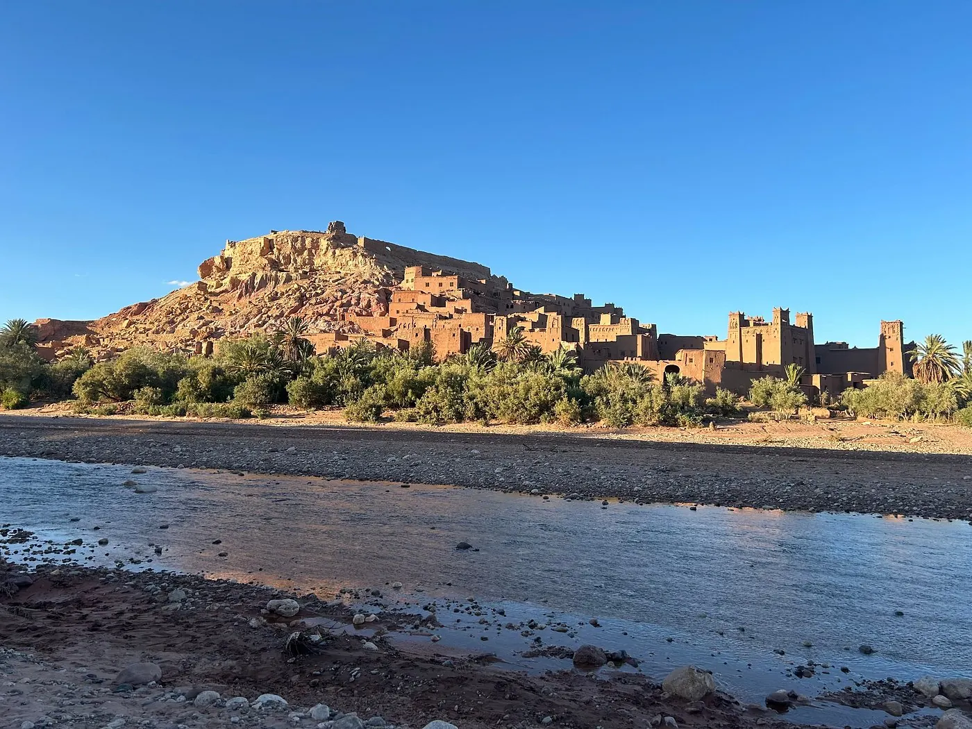 Panorama of the Ait Ben Haddou ksar above the river with the village and palms below