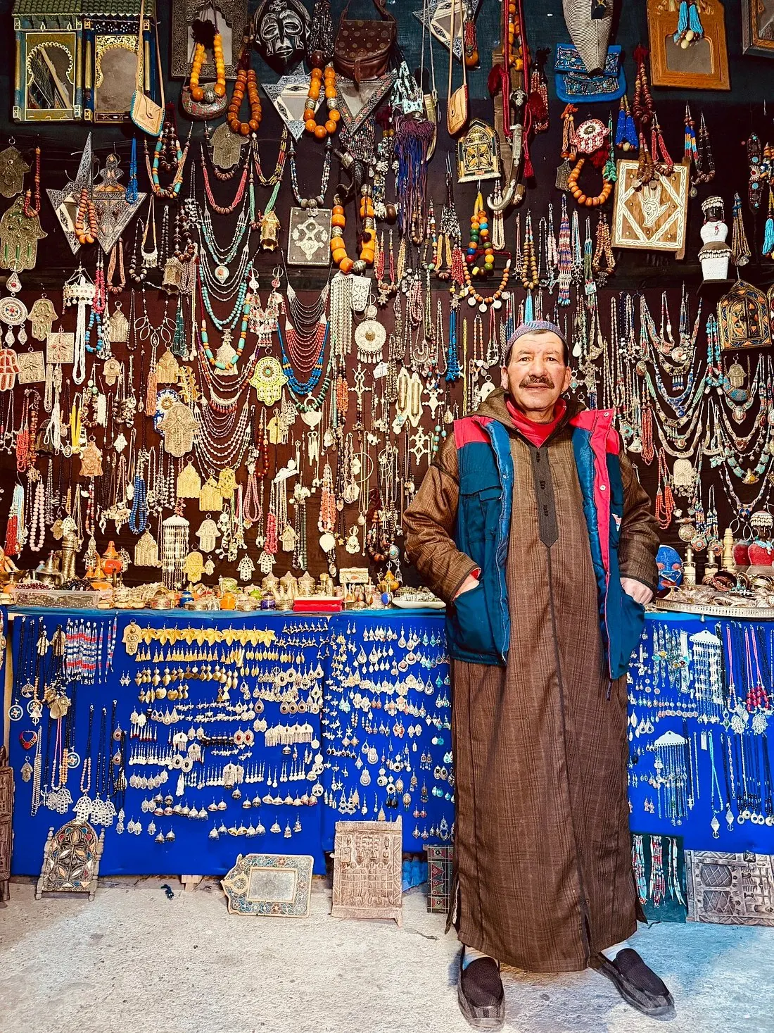 Smiling Berber merchant standing in front of his jewellery and silver stall in the souks