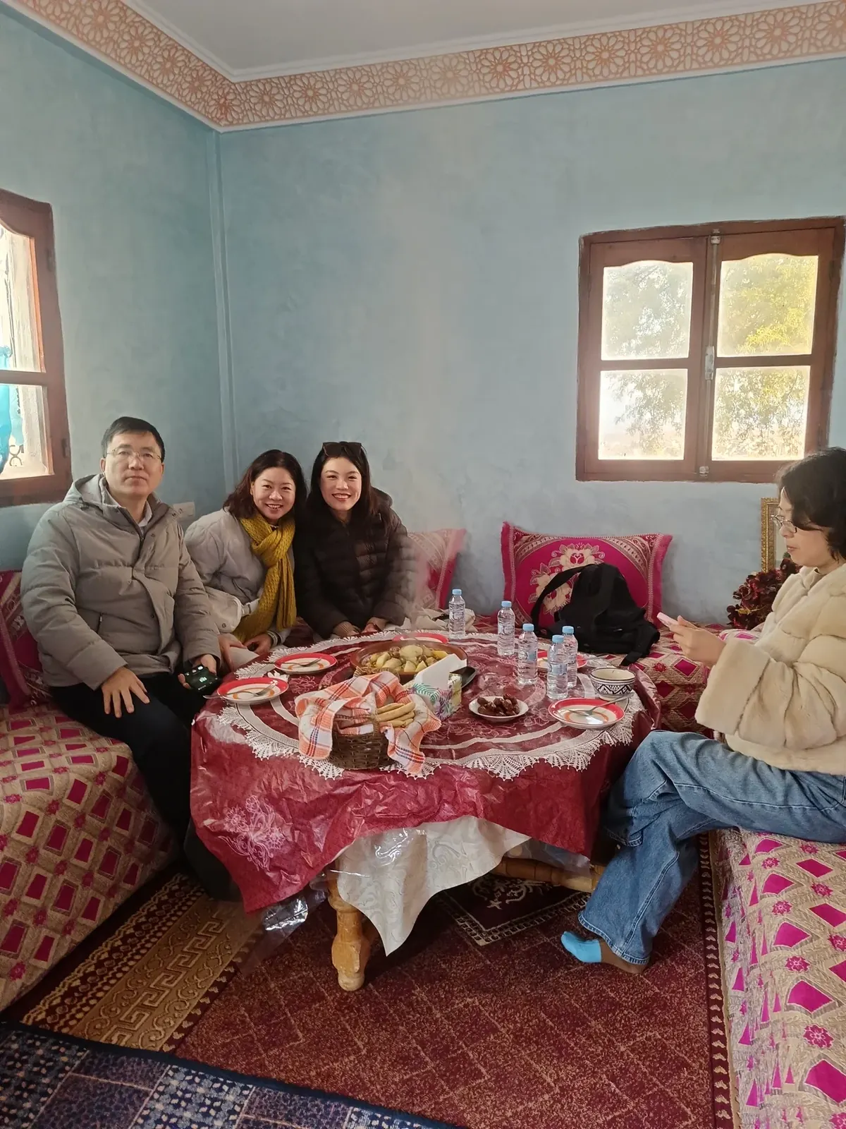 Group sharing a meal together around a family table inside a traditional Moroccan home