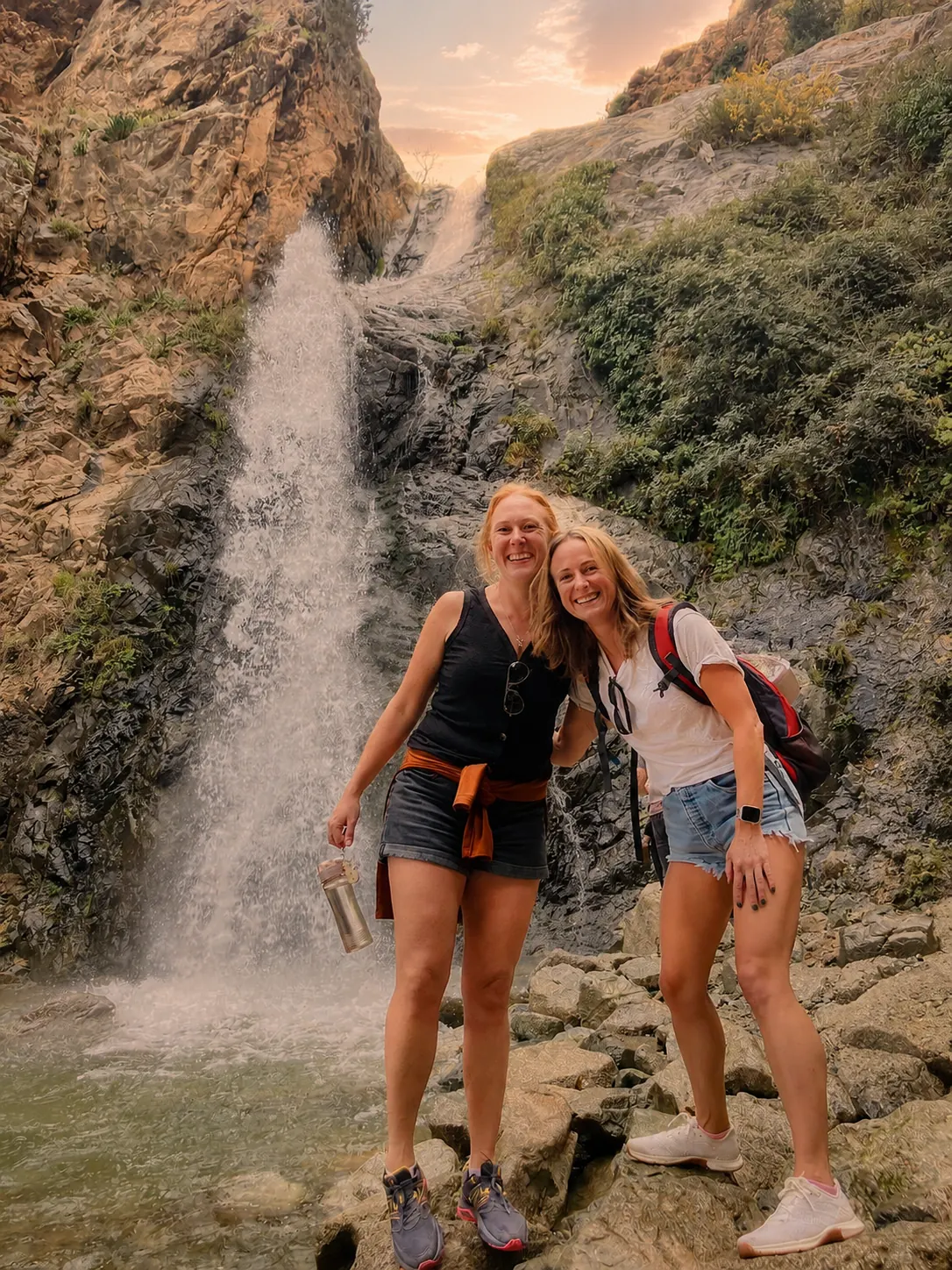 Two travellers smiling at the base of the Setti Fatma waterfall