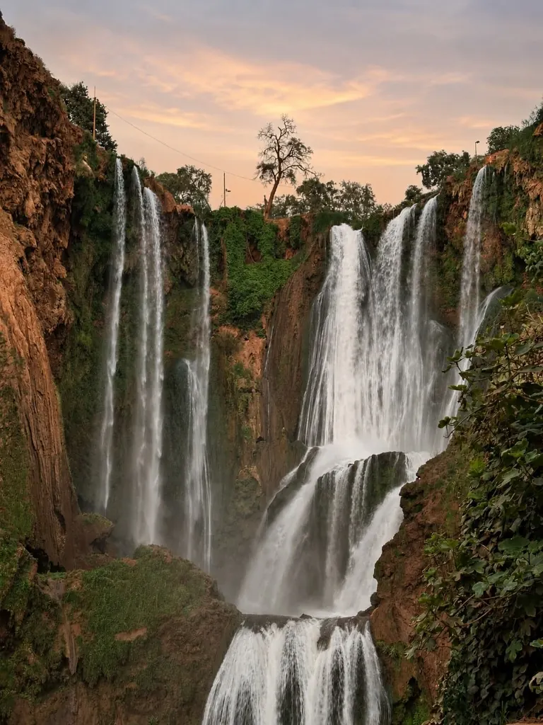 The Ouzoud Waterfalls at golden hour with mist rising through the gorge